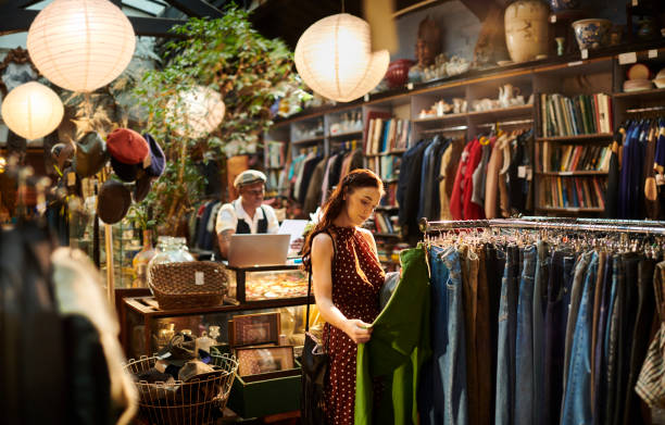 A woman shops for clothing in a stylish boutique, with a man working behind a counter in the background.