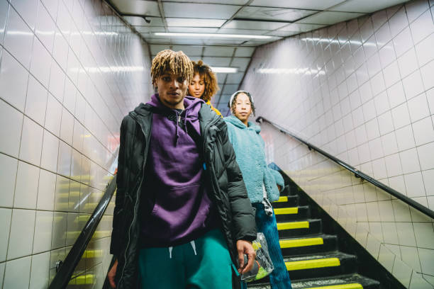 Three young people in streetwear fashion descend subway stairs, embodying the transition from underground to mainstream.